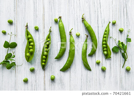 Pods of green peas with pea leaves   on a white  wooden background. Organic food. 70421661
