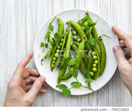 Green peas in a plate on a white wooden background. View from above. Green peas in a plate on a white wooden background. View from above. 70421663
