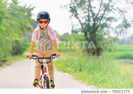 Young rider kid in helmet and sunglasses riding bicycle 70421775