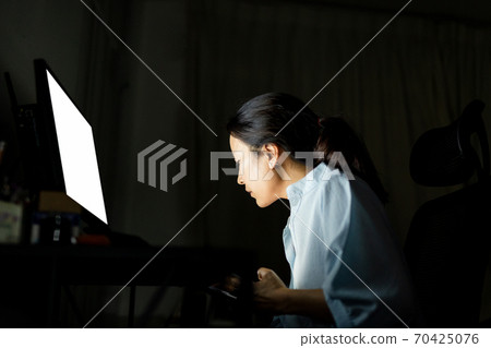 Businesswoman working on the computer late at night. 70425076