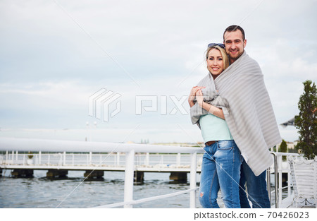 Beautiful young couple embracing, standing on a pier near water 70426023