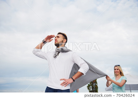 Happy young couple in stylish branded clothes, standing on the pier in the water. 70426024