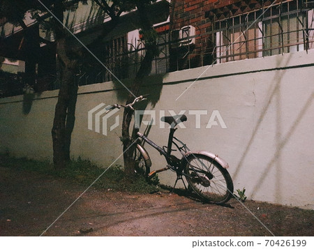 An old bike built on the wall in a poor neighborhood An old bike built on the wall in a poor neighborhood 70426199