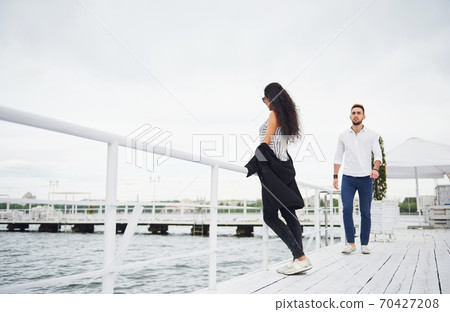 Happy young couple in love in a beautiful dress, posing on the pier near the water Happy young couple in love in a beautiful dress, posing on the pier near the water 70427208