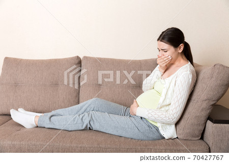 Pregnancy Morning Sickness. Pregnant Woman Having Nausea Feeling Bad in Sofa at the Home Pregnancy Morning Sickness. Pregnant Woman Having Nausea Feeling Bad in Sofa at the Home 70427767