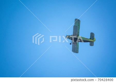 Retro green biplane plane in the blue sky Retro green biplane plane in the blue sky 70428400