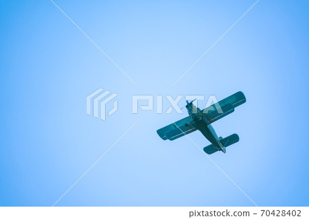 Retro green biplane plane in the blue sky Retro green biplane plane in the blue sky 70428402