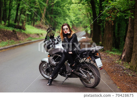 An attractive sexy girl on a sports motorbike posing outside 70428675
