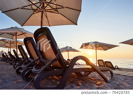 Scenic view of sandy beach on the beach with sun beds and umbrellas open against the sea and mountains. Hotel. Resort. Tekirova-Kemer Scenic view of sandy beach on the beach with sun beds and umbrellas open against the sea and mountains. Hotel. Resort. Tekirova-Kemer 70428785