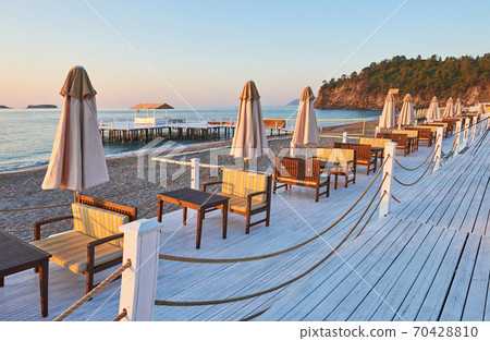 Scenic view of sandy beach on the beach with sun beds and umbrellas open against the sea and mountains. Hotel. Resort. Tekirova-Kemer Scenic view of sandy beach on the beach with sun beds and umbrellas open against the sea and mountains. Hotel. Resort. Tekirova-Kemer 70428810