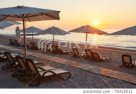 Scenic view of sandy beach on the beach with sun beds and umbrellas open against the sea and mountains. Hotel. Resort. Tekirova-Kemer Scenic view of sandy beach on the beach with sun beds and umbrellas open against the sea and mountains. Hotel. Resort. Tekirova-Kemer 70428812