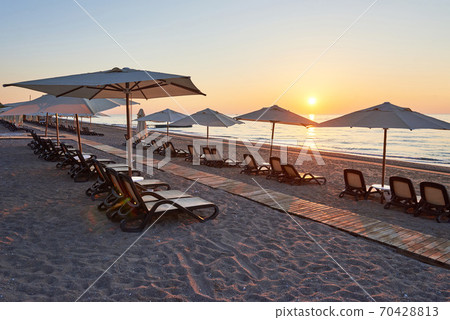 Scenic view of sandy beach on the beach with sun beds and umbrellas open against the sea and mountains. Hotel. Resort. Tekirova-Kemer Scenic view of sandy beach on the beach with sun beds and umbrellas open against the sea and mountains. Hotel. Resort. Tekirova-Kemer 70428813