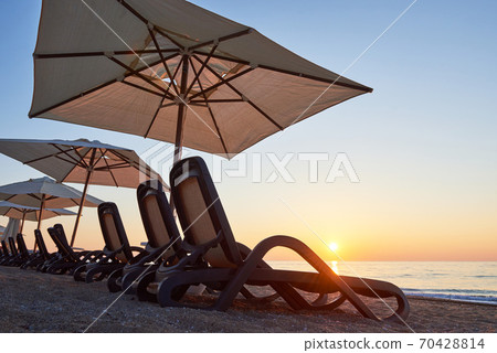 Scenic view of sandy beach on the beach with sun beds and umbrellas open against the sea and mountains. Hotel. Resort. Tekirova-Kemer Scenic view of sandy beach on the beach with sun beds and umbrellas open against the sea and mountains. Hotel. Resort. Tekirova-Kemer 70428814