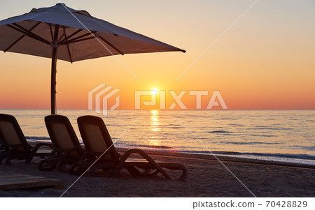 Scenic view of sandy beach on the beach with sun beds and umbrellas open against the sea and mountains. Hotel. Resort. Tekirova-Kemer Scenic view of sandy beach on the beach with sun beds and umbrellas open against the sea and mountains. Hotel. Resort. Tekirova-Kemer 70428829