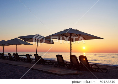 Scenic view of sandy beach on the beach with sun beds and umbrellas open against the sea and mountains. Hotel. Resort. Tekirova-Kemer Scenic view of sandy beach on the beach with sun beds and umbrellas open against the sea and mountains. Hotel. Resort. Tekirova-Kemer 70428830