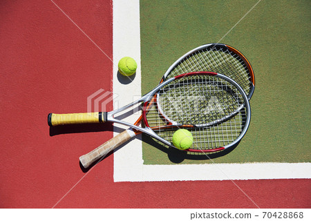 A tennis racket and new tennis ball on a freshly painted tennis court 70428868
