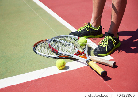 A tennis racket and new tennis ball on a freshly painted tennis court 70428869