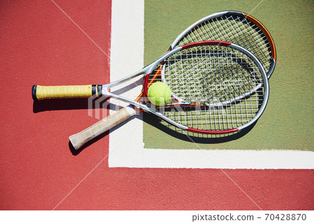 A tennis racket and new tennis ball on a freshly painted tennis court 70428870
