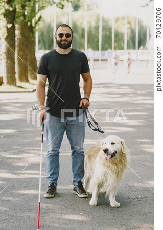 Blind man with guide dog in a summer city Blind man with guide dog in a summer city 70429706