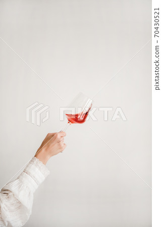 Womans hand holding and turning rose wine glass 70430521