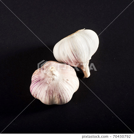 2 fresh garlic bulbs on a black background. 2 fresh garlic bulbs on a black background. 70430792