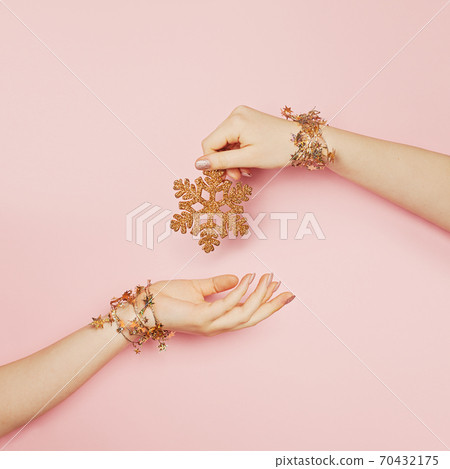 Xmas golden glitter decoration snowflake in young woman hand on pink background 70432175
