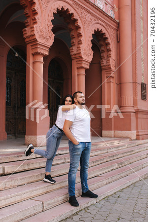 Two belowed people walking in the city. Beautiful couple in denim and white t-shirt have fun Two belowed people walking in the city. Beautiful couple in denim and white t-shirt have fun 70432196