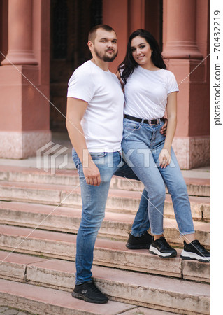 Two belowed people walking in the city. Beautiful couple in denim and white t-shirt have fun Two belowed people walking in the city. Beautiful couple in denim and white t-shirt have fun 70432219