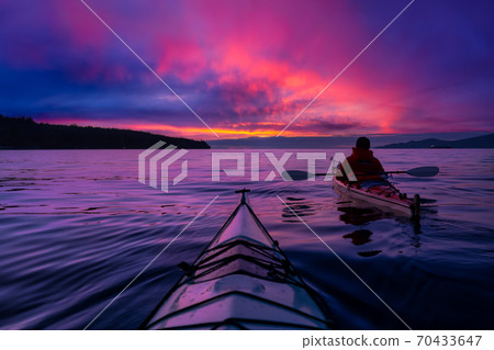 Adventure Man on a Sea Kayak is kayaking at Sunset 70433647