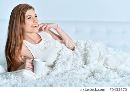 Beautiful young woman with cup of coffee 70433870