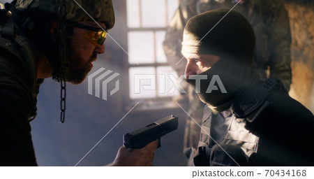 Angry soldier interrogating mature terrorist Angry soldier interrogating mature terrorist 70434168