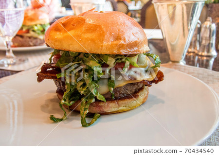 CHICAGO, ILLINOIS, UNITED STATES - DEC 12th, 2015: gourmet cheeseburger with french fries in background in a luxury hotel restaurant CHICAGO, ILLINOIS, UNITED STATES - DEC 12th, 2015: gourmet cheeseburger with french fries in background in a luxury hotel restaurant 70434540