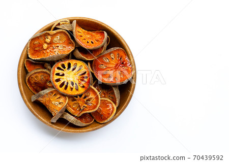 Dried bael fruit in wooden bowl on white background. 70439592