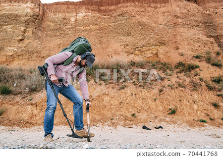 Man with metal detector searching for lost treasures on the beach Man with metal detector searching for lost treasures on the beach 70441768