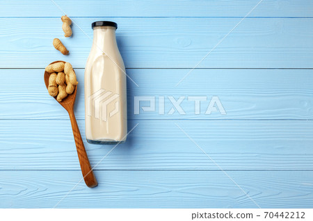 Vegan peanut milk in glass bottle with peanuts on wooden board Vegan peanut milk in glass bottle with peanuts on wooden board 70442212