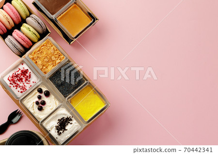 Mousse desserts in square plastic boxes with different toppings on pink table 70442341