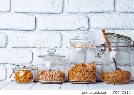 Glass jars with granola and muesli, front view Glass jars with granola and muesli, front view 70442513