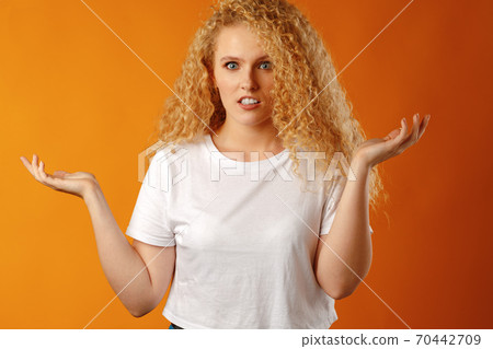 Amazed young woman gesturing that she doesn't know 70442709