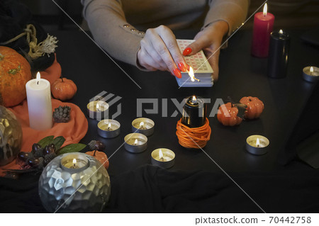 Blurred hand with matchstick, lighting a Candle. Halloween esoteric 70442758