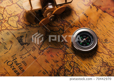Old compass discovery and wooden plane on vintage paper antique world map Old compass discovery and wooden plane on vintage paper antique world map 70442970