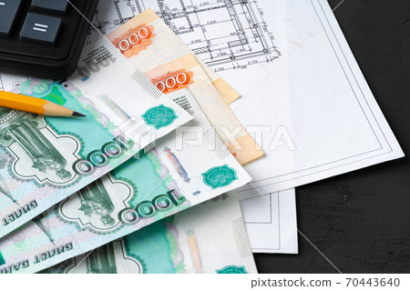 Russian roubles stack on blueprints wth calculator. Renovation, building expenses concept Russian roubles stack on blueprints wth calculator. Renovation, building expenses concept 70443640