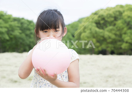 Girl inflating a rubber balloon Girl inflating a rubber balloon 70444308