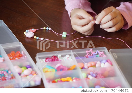 A girl in first grade enjoys playing with beads at home. A girl in first grade enjoys playing with beads at home. 70444671