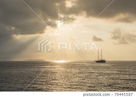 Sunset over the Indian ocean with Maldivian islands on the horizon and silhouette of ship with masts Sunset over the Indian ocean with Maldivian islands on the horizon and silhouette of ship with masts 70445587