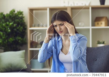 Young stressed woman touching temples with hands and feeling bad Young stressed woman touching temples with hands and feeling bad 70447911