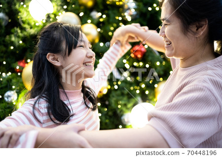 Happy asian family,beautiful woman, child girl stand and dancing around a Christmas tree,celebrating Christmas,loving mother, daughter enjoying,fun at home with new year decoration,celebration concept 70448196