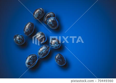 Isolated shot of plums splashing with water, isolated on blue background. Isolated shot of plums splashing with water, isolated on blue background. 70449360