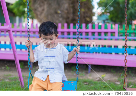 Young Asian boy play a iron swinging at the playground under the sunlight in summer. 70450836