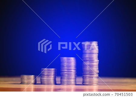 Savings, increasing columns of gold coins, piles of gold coins arranged as a graph on wooden table with black wall. Savings, increasing columns of gold coins, piles of gold coins arranged as a graph on wooden table with black wall. 70451503