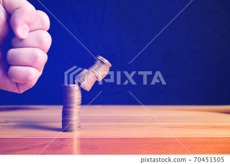 Hand punch the increasing columns of gold coins on wooden table with black wall, piles of gold coins breaking by hammer hand, business bankrupt concept Hand punch the increasing columns of gold coins on wooden table with black wall, piles of gold coins breaking by hammer hand, business bankrupt concept 70451505